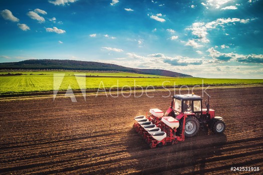 Picture of Farmer with tractor seeding crops at field aerial drone view